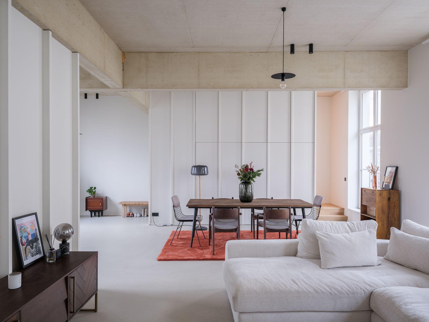 Leef- en eetruimte met zichtbetonbalken en ingebouwde kasten in een woning van het project Nieuwland 28-40 in Gent.